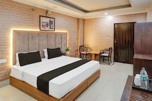 Une chambre d’hôtel avec un lit, une table de chevet, une chaise et une petite table sur laquelle se trouve une bouteille.