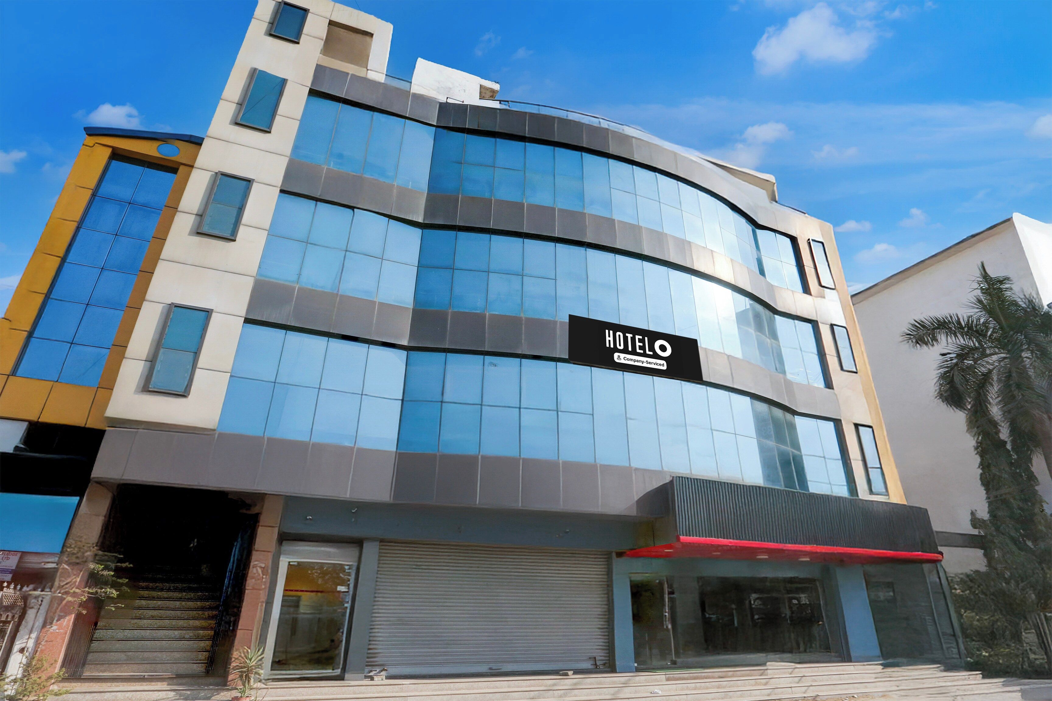 A modern hotel building with a glass facade and a sign indicating it is company-serviced.