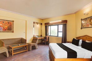 Ein Hotelzimmer mit einem Bett, einem Schreibtisch, einem Sessel, einer Couch und einem Bild an der Wand.