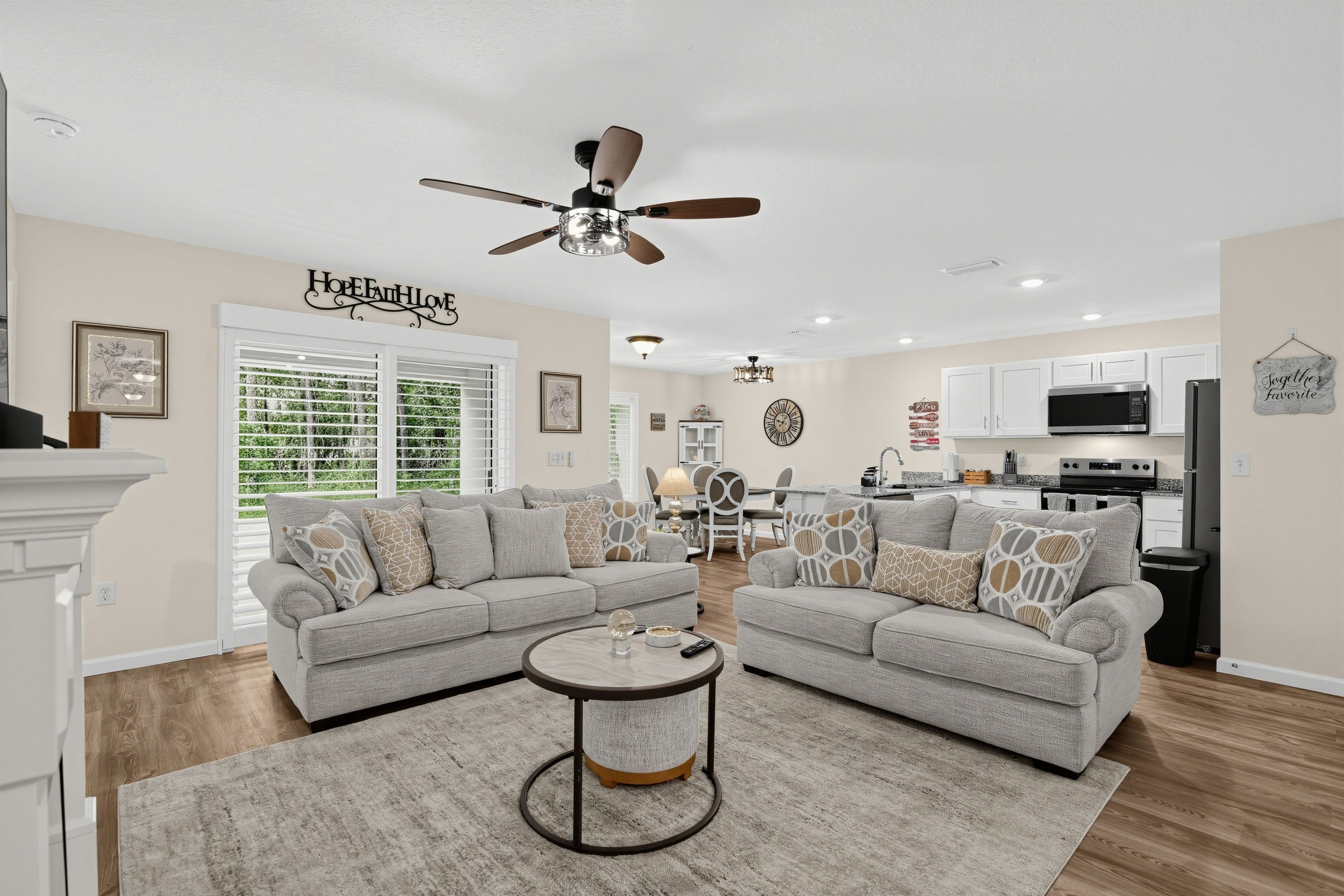 A modern living room with a sectional sofa, a round coffee table, and a ceiling fan.