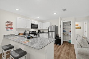 Una cocina moderna con armarios blancos, un refrigerador de acero inoxidable, un microondas y una encimera de granito.