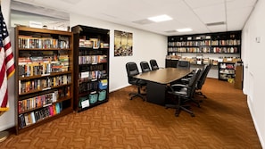 A conference room with a long table and chairs, surrounded by bookshelves filled with books. - 525 El Matador 1 Bedroom Condo (Fort Walton Beach)