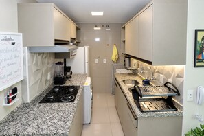 A compact kitchen with a gas stove, coffee maker, and a sink. - VG Fun Praia do Futuro (Fortaleza)