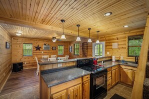 Een houten cabin met keuken, eethoek en plafondventilator.
