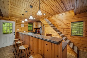 Ein Holzinnenraum mit Küche, Barbereich und einer Treppe.