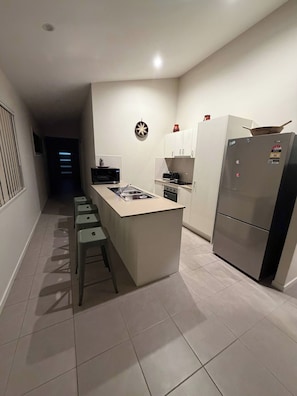 A modern kitchen with a central island, a refrigerator, and a microwave. - Luxurious Family Home Away From Home, Comfortable (Park Ridge)