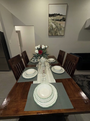 A dining table set with white plates, glasses, and a vase with flowers. - Luxurious Family Home Away From Home, Comfortable (Park Ridge)