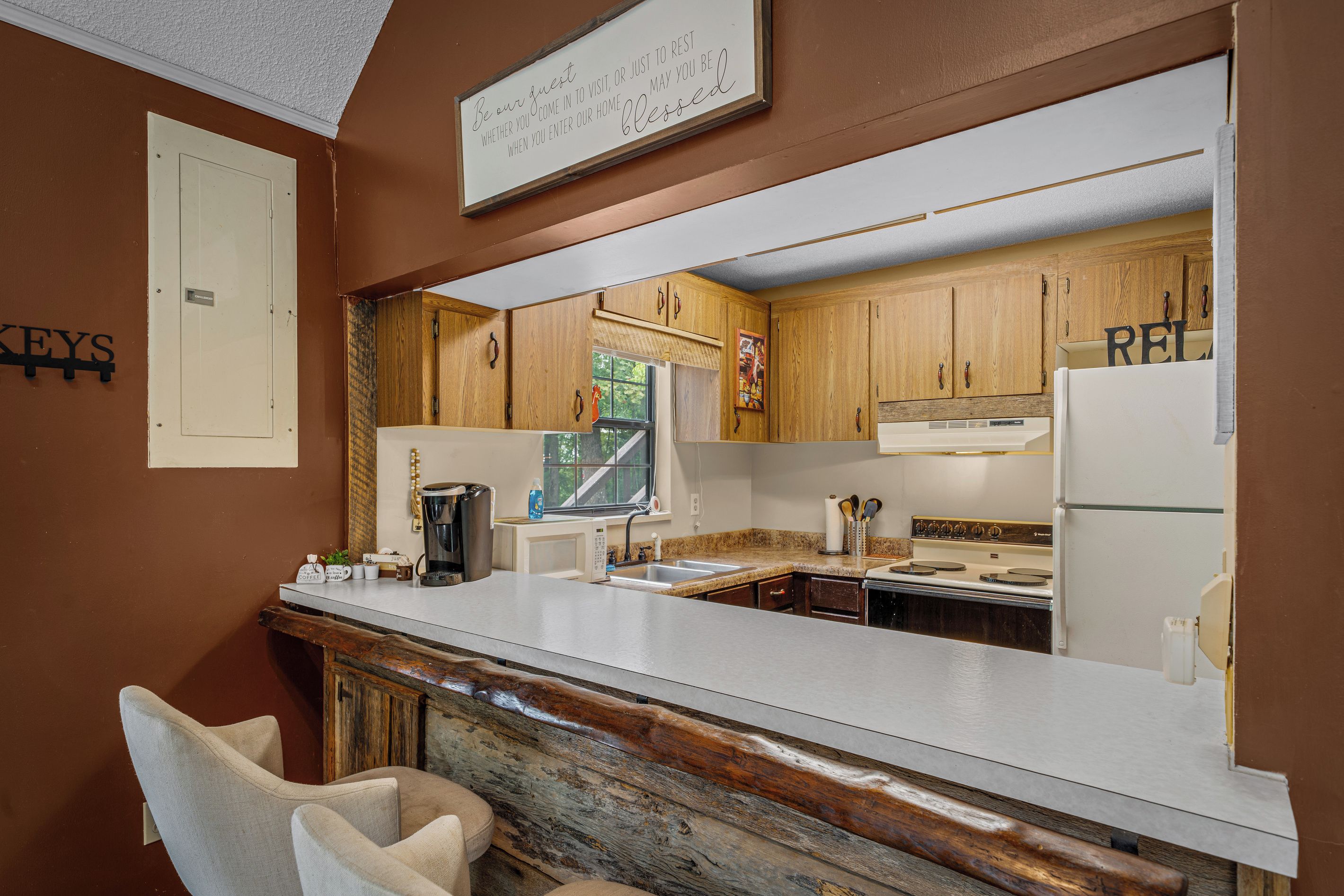A kitchen with wooden cabinets, a white countertop, and a coffee machine.