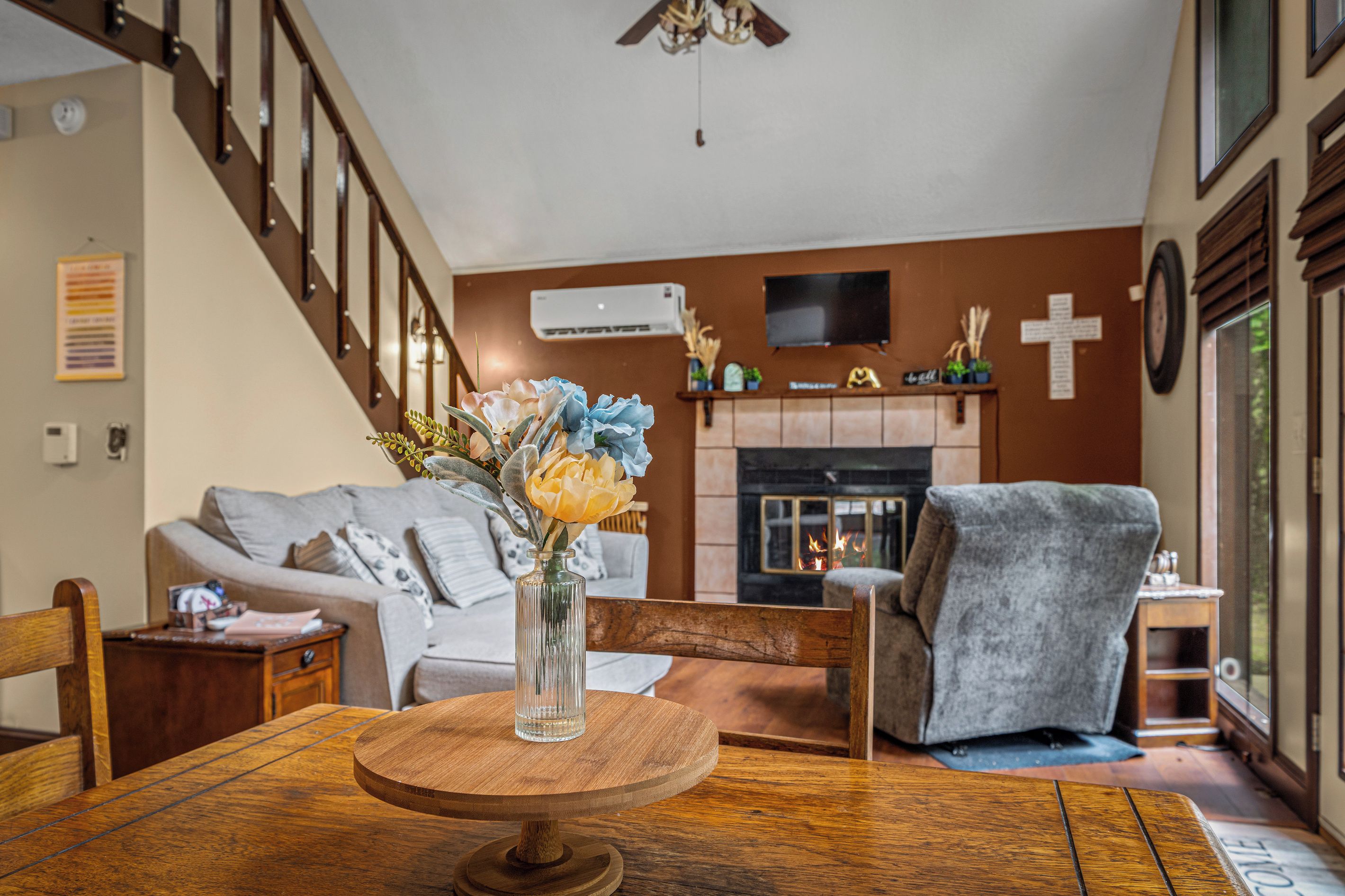 A living room with a fireplace, a sofa, a coffee table with a vase, and a staircase.
