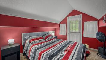 A bedroom with a bed, nightstand, and a standing fan.