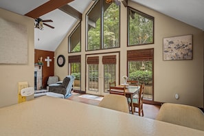 A spacious room with a high ceiling, large windows, a dining area, and a cozy seating arrangement. - Cozy Cabin at Cash Cabins-sleep 5 (Mentone)