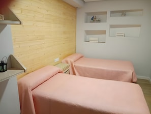 A room with two beds, wooden paneling on the walls, and built-in shelves with items on them. - Apartment 'Alojamiento Rural La Tahona Gorafe' with Wi-Fi (Gorafe)