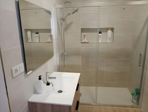 A modern bathroom with a white sink, mirror, and shower enclosure. - Apartment 'Alojamiento Rural La Tahona Gorafe' with Wi-Fi (Gorafe)