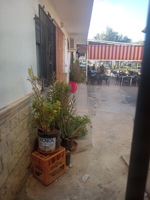 A courtyard with outdoor seating, potted plants, and a building with a barred window. - Apartment 'Alojamiento Rural La Tahona Gorafe' with Wi-Fi (Gorafe)
