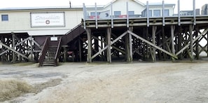 Eine Holzsteganlage mit einer Treppe, die zu einem Gebäude namens 'Strandhütte' führt.