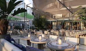 An outdoor dining area with round tables, chairs, and potted plants. - Mercury Suites Elegant Apartment (St. Julian's)