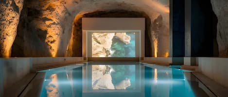 An indoor swimming pool with a large screen displaying a rocky landscape.