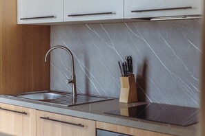 A kitchen with a modern faucet, a marble backsplash, and a knife block. - Mercury Suites Sleek Apt With Pool Access (St. Julian's)