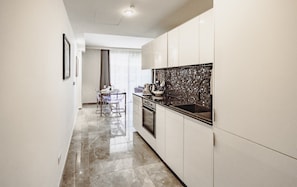 A modern kitchen with a tiled backsplash, stainless steel appliances, and a dining area with a glass table and chairs. - Mercury Suites Prestige Stay, Pool Access (St. Julian's)
