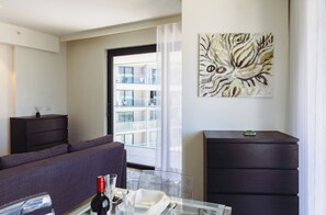 A modern living room with a sofa, a glass coffee table, and a painting on the wall. - Mercury Suites Refined Living, Pool Access (St. Julian's)
