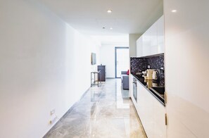 A modern kitchen with a black tiled backsplash, a grey sofa, and a dining table. - Mercury Suites Refined Living, Pool Access (St. Julian's)