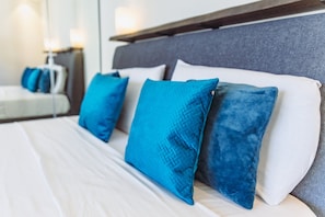 A bed with white linens and three pillows in varying shades of blue. - Mercury Suites Refined Living, Pool Access (St. Julian's)