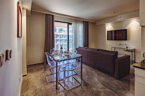 A modern hotel room with a dining area, a sofa, a flat-screen TV, and a view of the city. - Mercury Suites Luxe Living, Pool Access (St. Julian's)