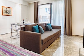 Ein modernes Wohnzimmer mit einem braunen Sofa, einem Glastisch und einem Essbereich mit Tisch und Stühlen.