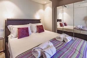 Habitación de hotel con cama, almohadas, un espejo y toallas.