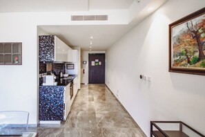 A hallway with a kitchen area on the left, a painting on the right, and a door at the end. - Mercury Suites 2BR Luxury Hideaway, Pool Access (St. Julian's)