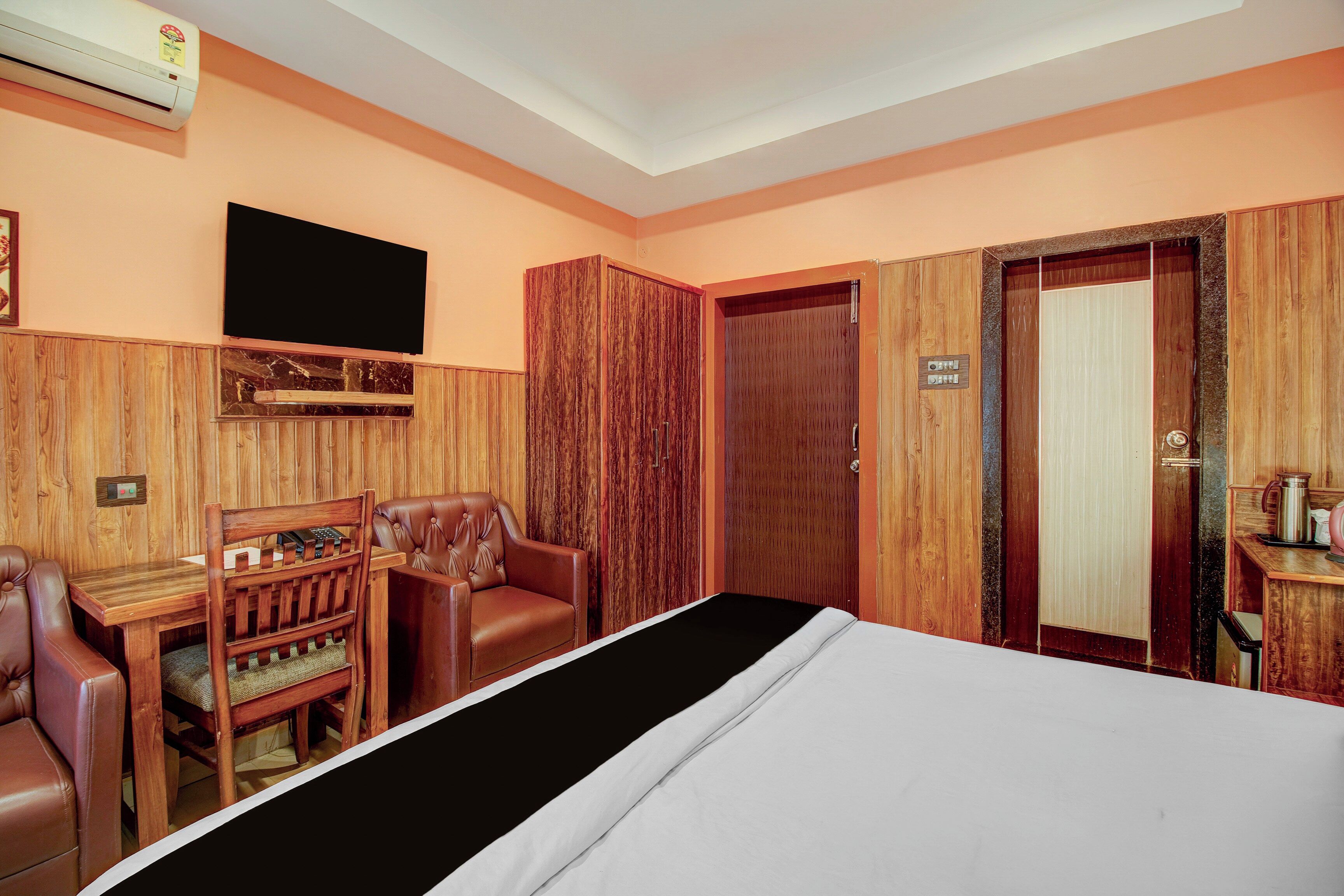 Una habitación de hotel con una cama, un escritorio, una silla, un televisor y un armario.