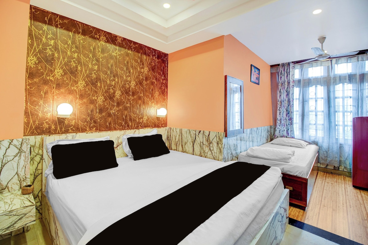 A hotel room with a large bed, a bedside table, a mirror, and a window with curtains.