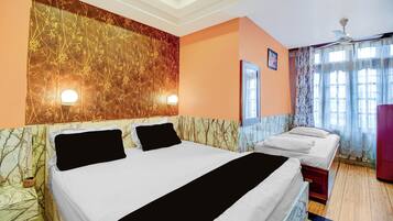 A hotel room with a large bed, a bedside table, a mirror, and a window with curtains.