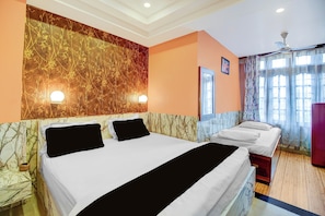 A hotel room with a large bed, a bedside table, a mirror, and a window with curtains. - Super Collection O Downtown Hospital (Guwahati)