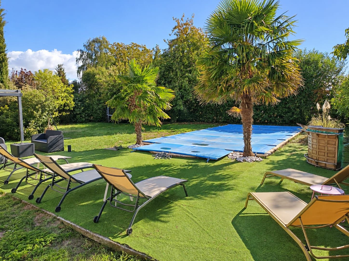 Quintal com grama sintética, piscina e móveis para área externa.
