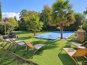 A backyard with artificial grass, a pool, and outdoor furniture.