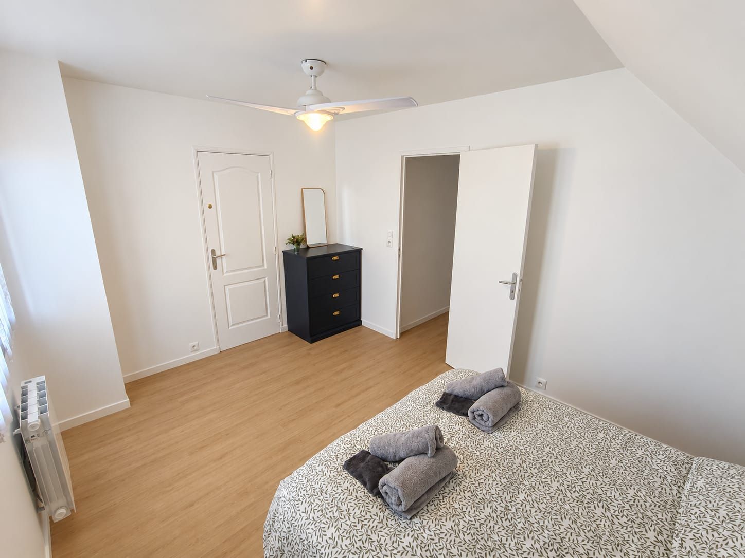 Ein Schlafzimmer mit einem Bett, einem Schminktisch, einem Deckenventilator und einer Tür.