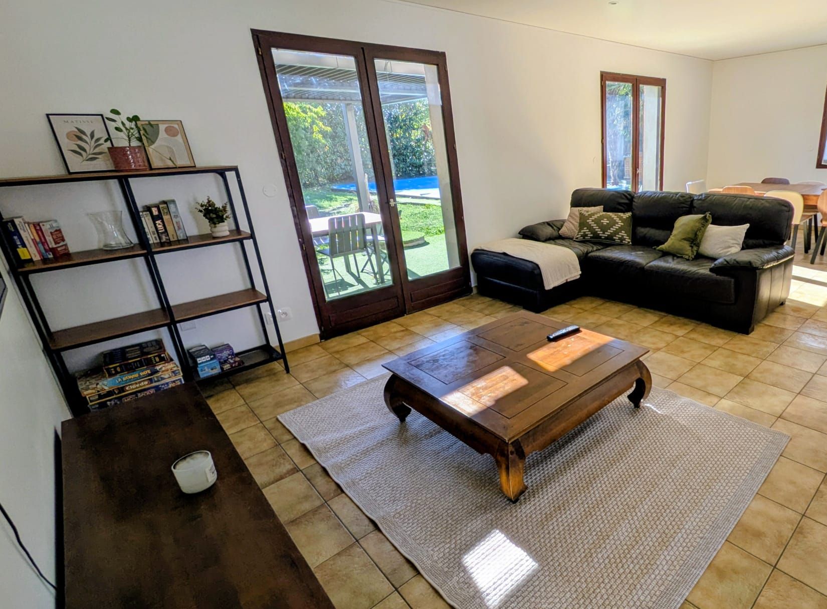 Ein Wohnzimmer mit einer Couch, einem Couchtisch, einem Bücherregal und einer Schiebetür zu einer Terrasse.