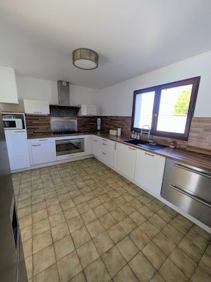 A modern kitchen with white cabinets, a stainless steel range, and a window with a view.