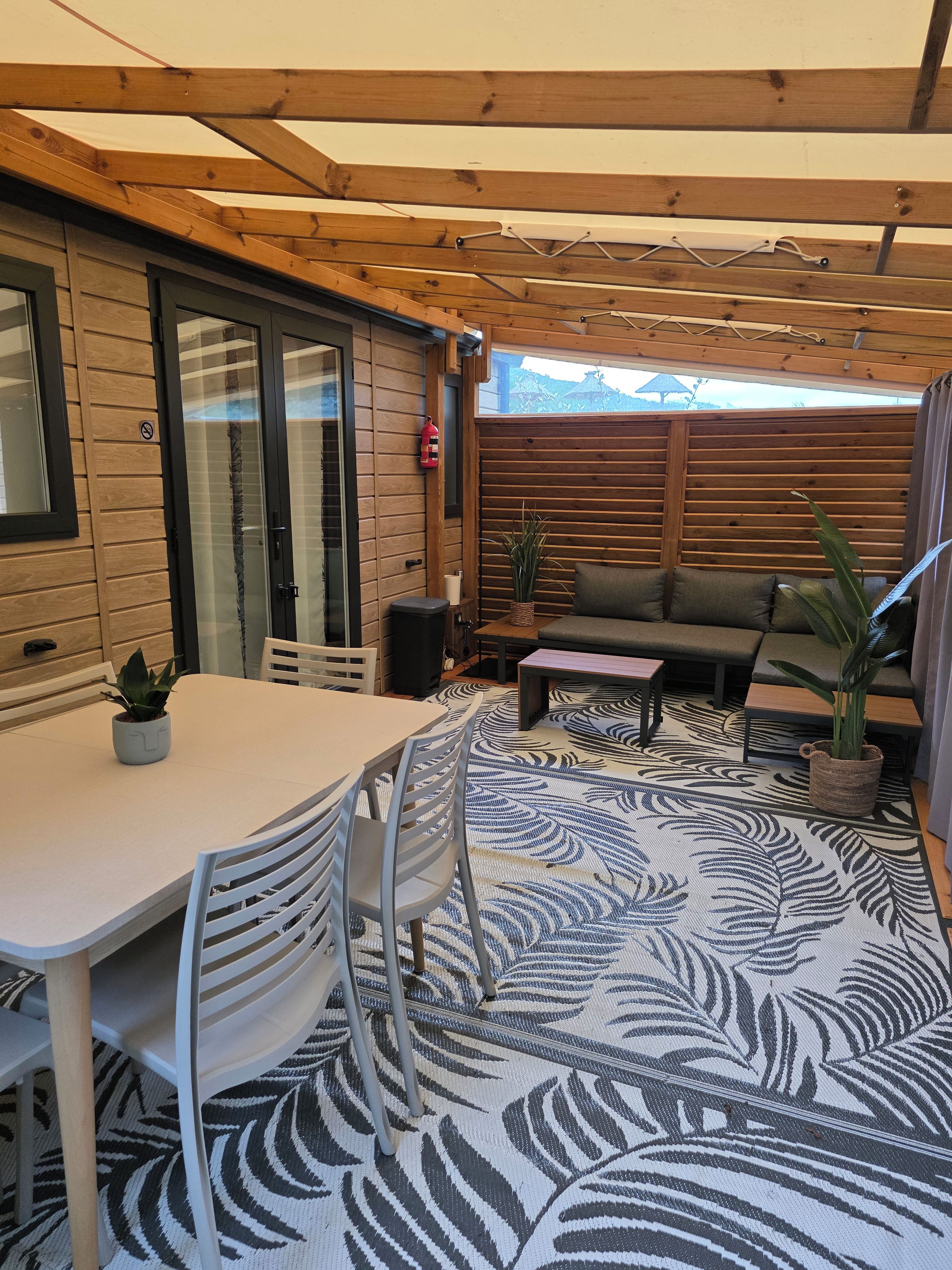 Un patio cubierto con una mesa, sillas, un sofá y un tapete estampado.