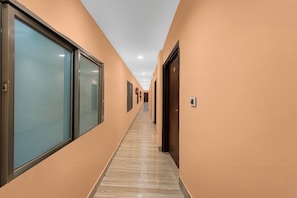 A corridor with glass doors on one side and wooden doors on the other, leading to a hallway with a tiled floor. - Super Collection O Frazer Road Patna (Patna)