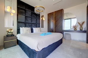 A modern bedroom with a large bed, a dark headboard, a chandelier, and a large mirror. - Superlative Skyline Apartment, Mercury Tower (St. Julian's)