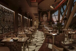 A restaurant with a checkered floor, high ceilings, and a large mural. Tables are set with wine glasses and plates. - Mercury Tower Modern Apartment (St. Julian's)