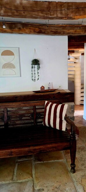 A rustic wooden bench with a striped pillow, a wall-mounted plant, and a framed picture. - Country house at the foot of Turenne Castle (Turenne)