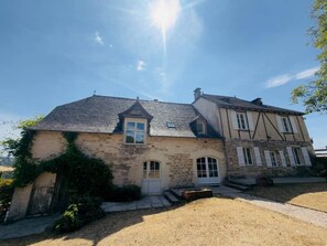 A two-story stone house with a sloped roof, a front door, and a small porch area. - Country house at the foot of Turenne Castle (Turenne)