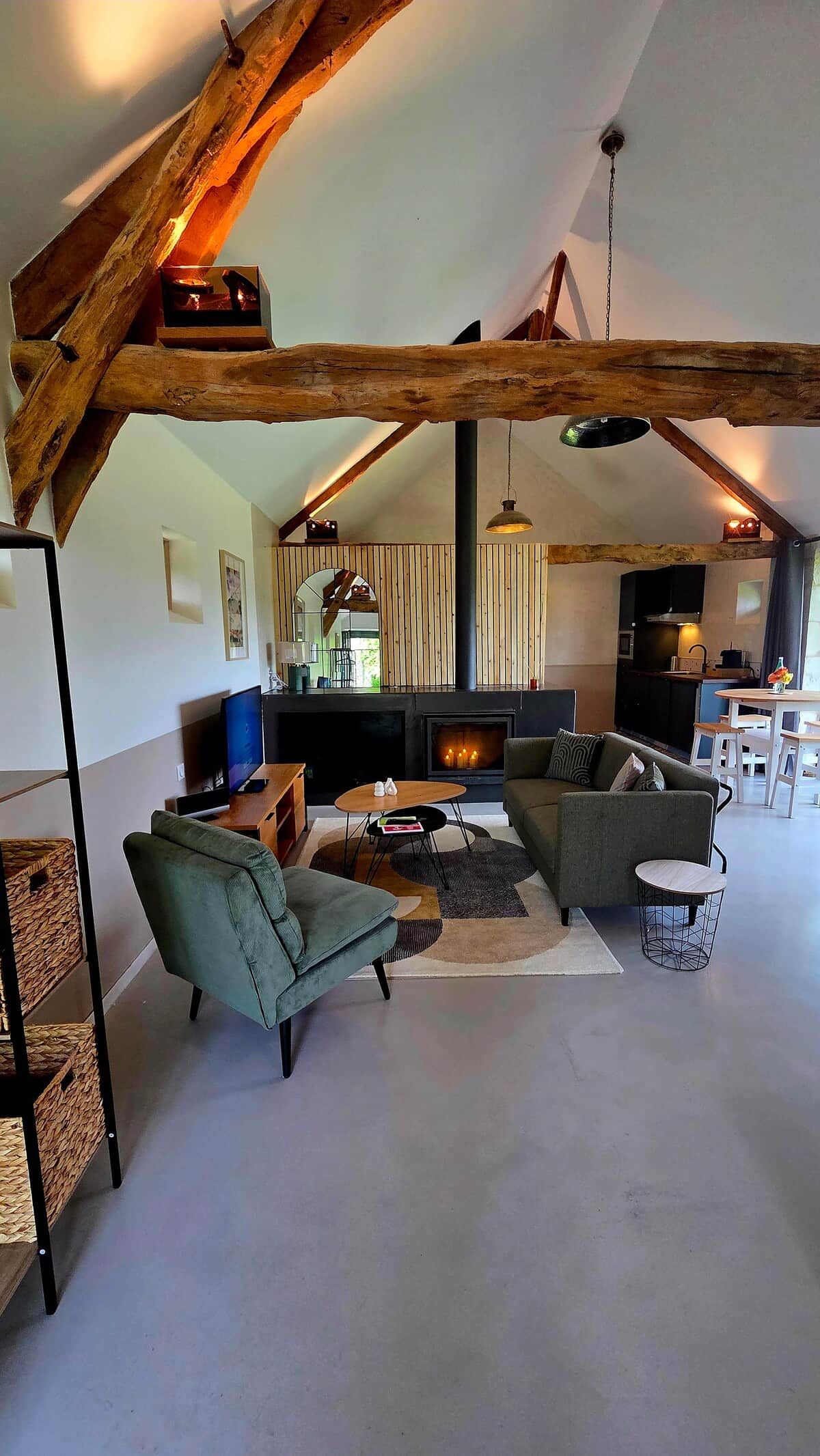 Ein großzügiges Loft mit freiliegenden Holzbalken, Kamin, Fernseher und Essbereich.