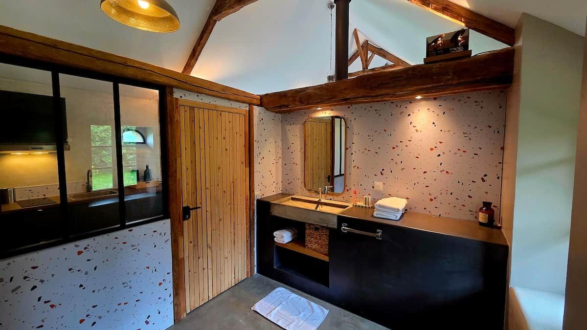 Ein Badezimmer mit Holztür, Waschbecken mit Spiegel und einem Handtuch auf dem Boden.