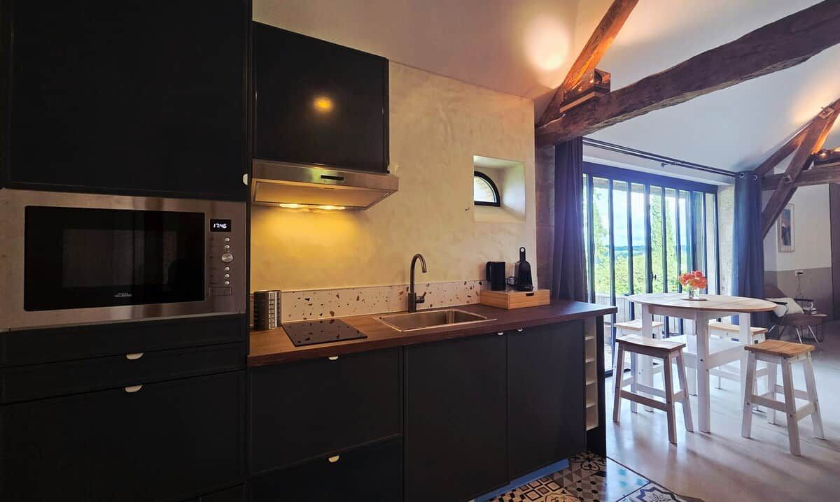 A modern kitchen with a built-in microwave, a stainless steel range hood, and a double sink.
