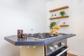 A kitchen with a gas stove, a coffee maker, and a fruit bowl. - Lovely Flat near Royal Yacht Britannia (Edinburgh)