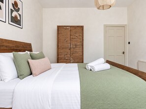 A bedroom with a bed, pillows, a wardrobe, and a door. - Lovely Flat near Royal Yacht Britannia (Edinburgh)